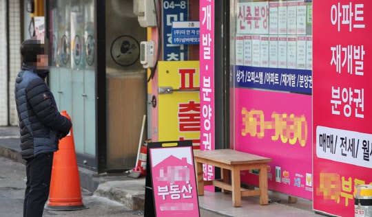 서울 서대문구의 한 부동산 사무실 앞에서 한 시민이 인근 아파트들의 매매와 전세, 월세 가격을 살펴보고 있다. <연합뉴스>